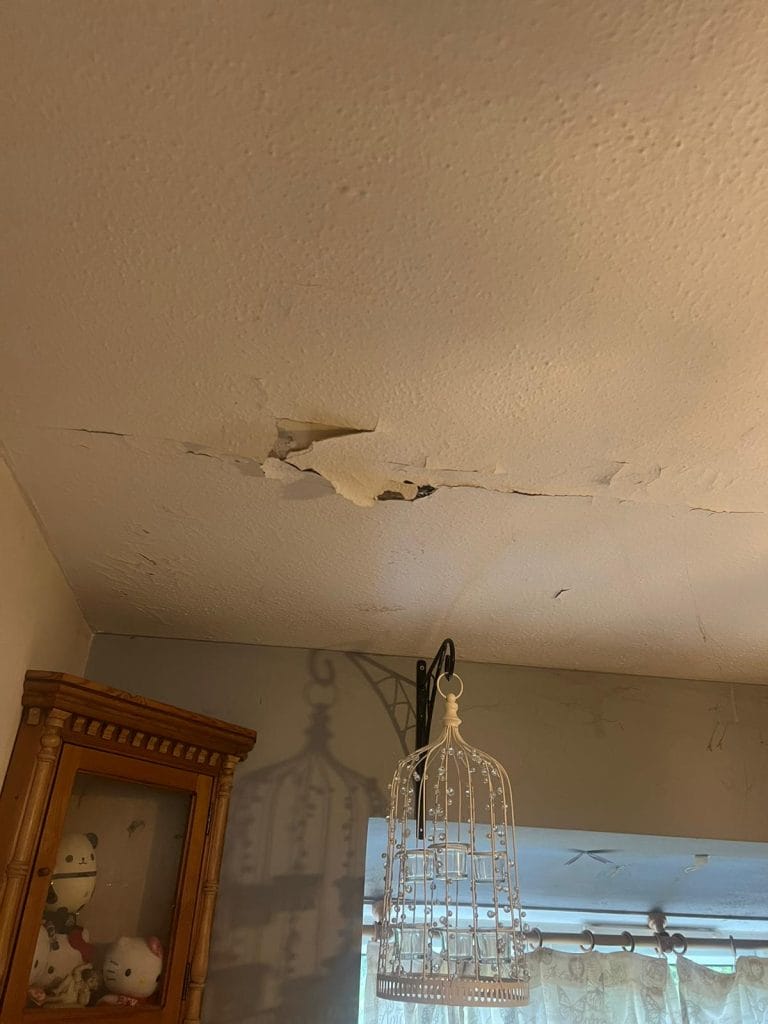 Ceiling with cracked and peeling plaster above a doorway